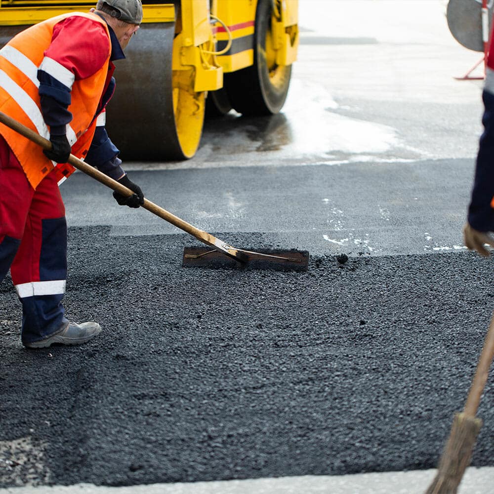 asphalt contractors paving over worn out and faded asphalt